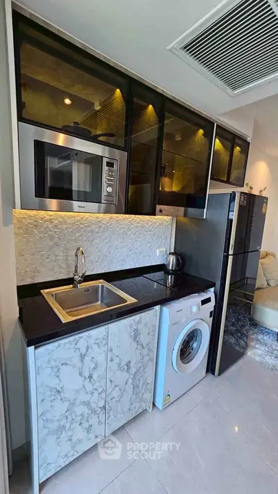 Modern kitchen with marble countertops, built-in microwave, and washing machine in sleek apartment.