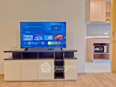 Modern living room with sleek TV stand and view into stylish kitchen area.
