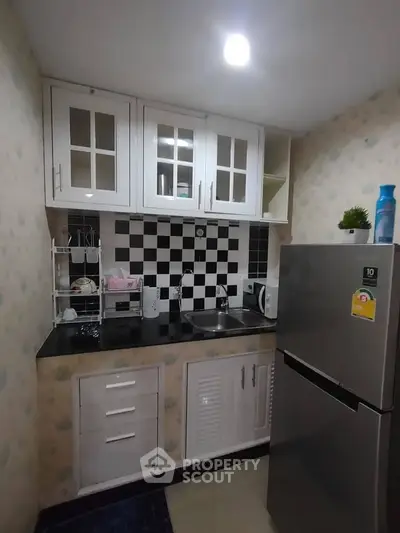 Charming compact kitchen with modern appliances and stylish black-and-white backsplash, perfect for cozy urban living.