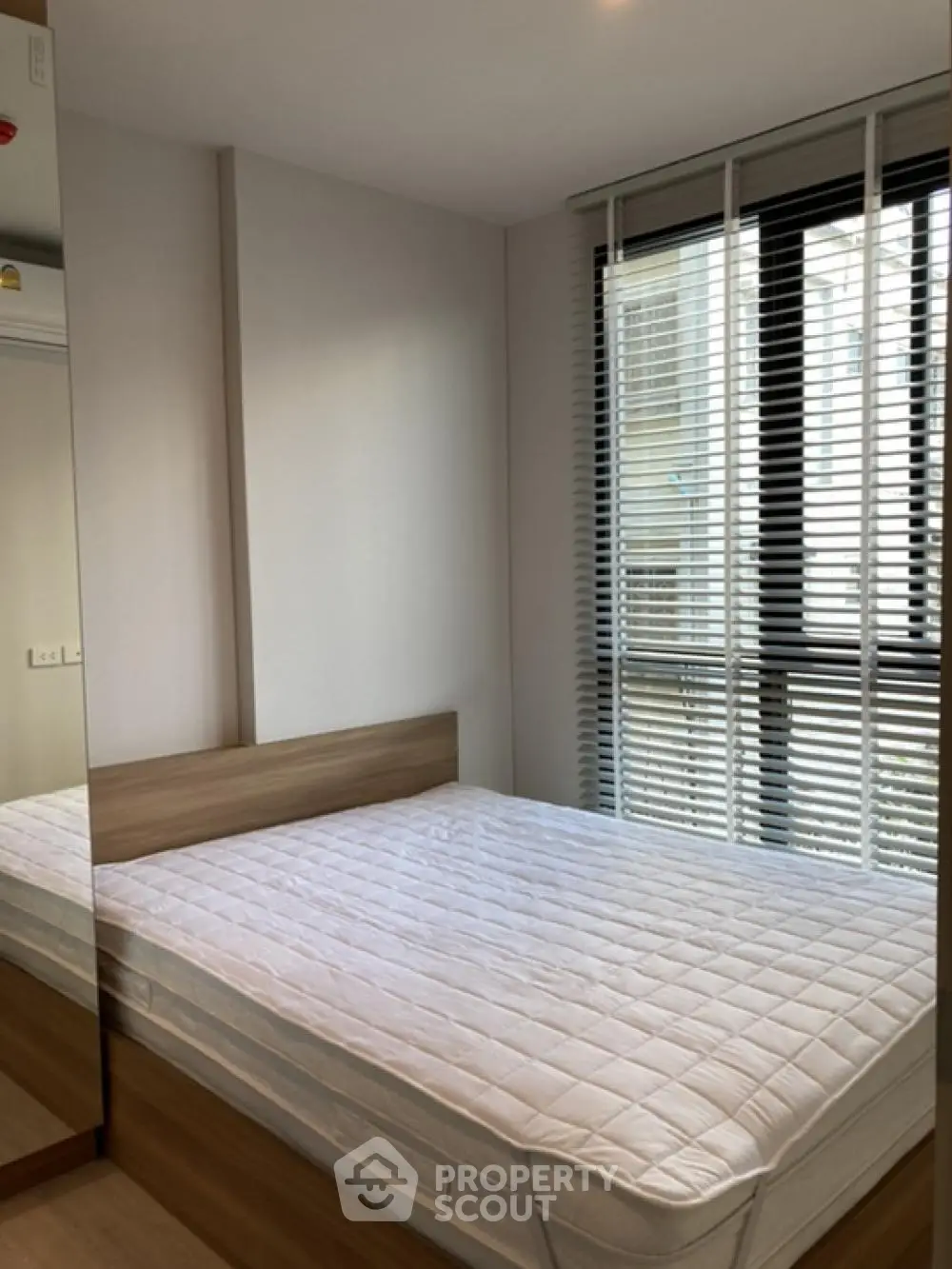 Modern bedroom with large window and mirrored wardrobe in stylish apartment