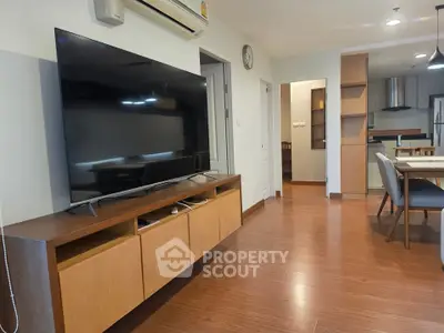 Modern living room with large TV and open kitchen layout in stylish apartment.