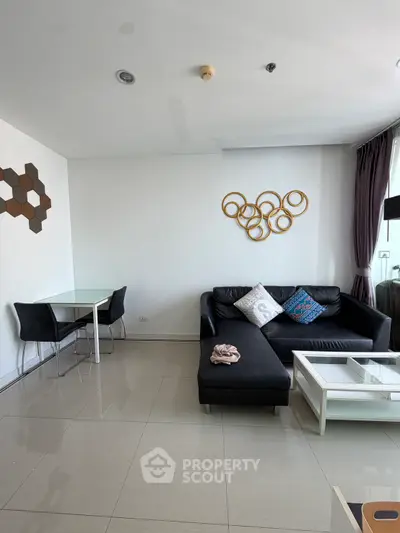 Modern living room with sleek black sofa and stylish wall decor in a bright apartment.
