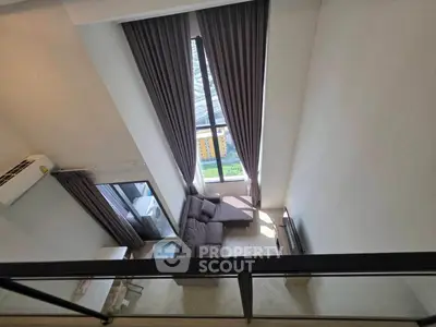 Spacious modern living room with high ceilings and large windows offering stunning city views.