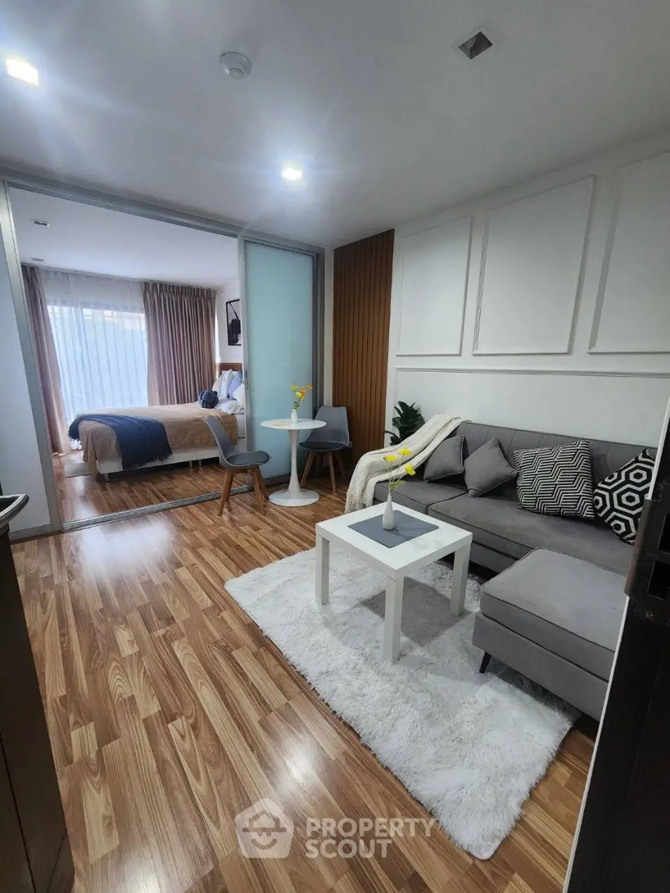 Modern living room with cozy seating and stylish decor leading to a chic bedroom.