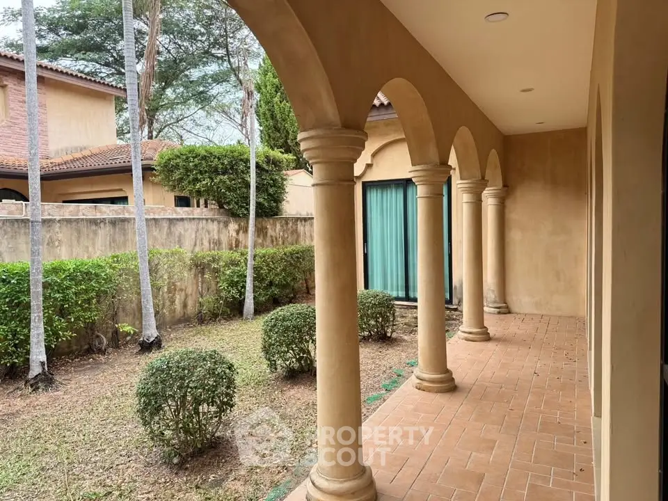Elegant Mediterranean-style exterior with arched columns and lush garden view.
