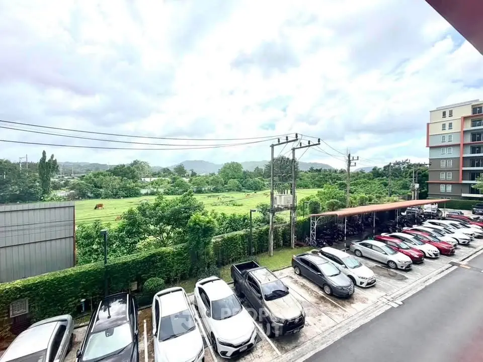 Scenic view from apartment balcony overlooking parking and lush greenery.