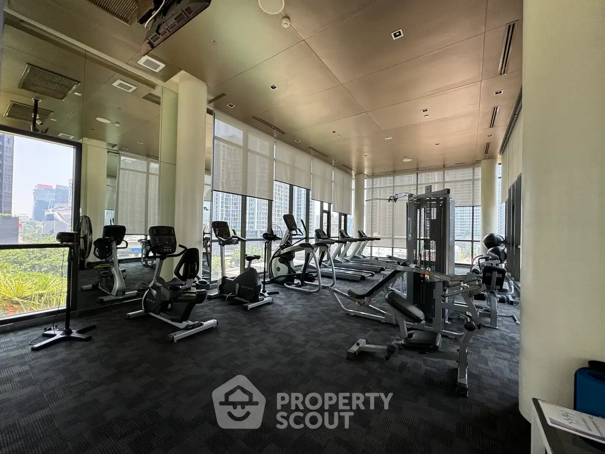 Spacious modern gym with city view, featuring state-of-the-art fitness equipment and large windows.