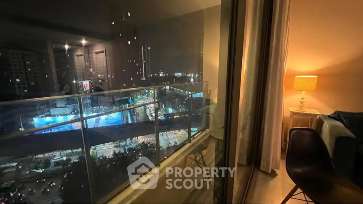 Stunning city view from modern apartment balcony at night, featuring cozy interior lighting.