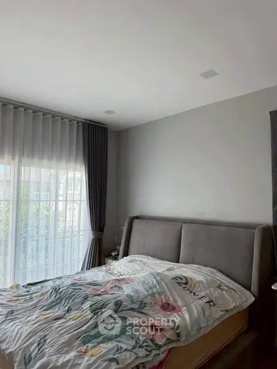 Cozy bedroom with large window and elegant curtains, perfect for relaxation.