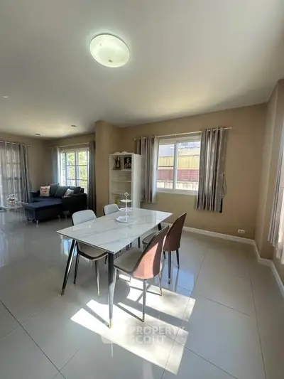 Spacious modern dining area with elegant table and chairs, abundant natural light, and stylish decor.