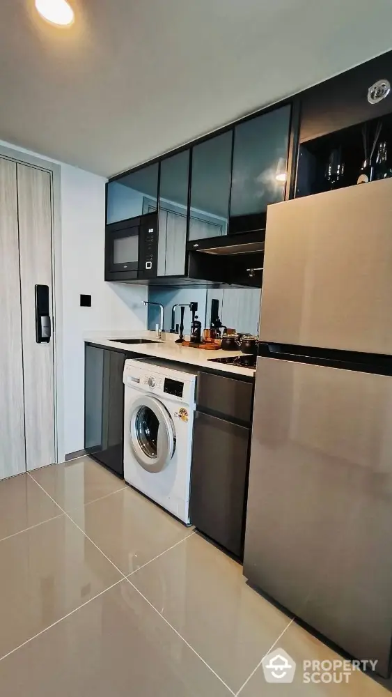 Modern kitchen with sleek appliances and washing machine in compact layout