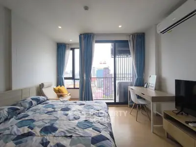 Spacious bedroom with city view, modern decor, and natural light.