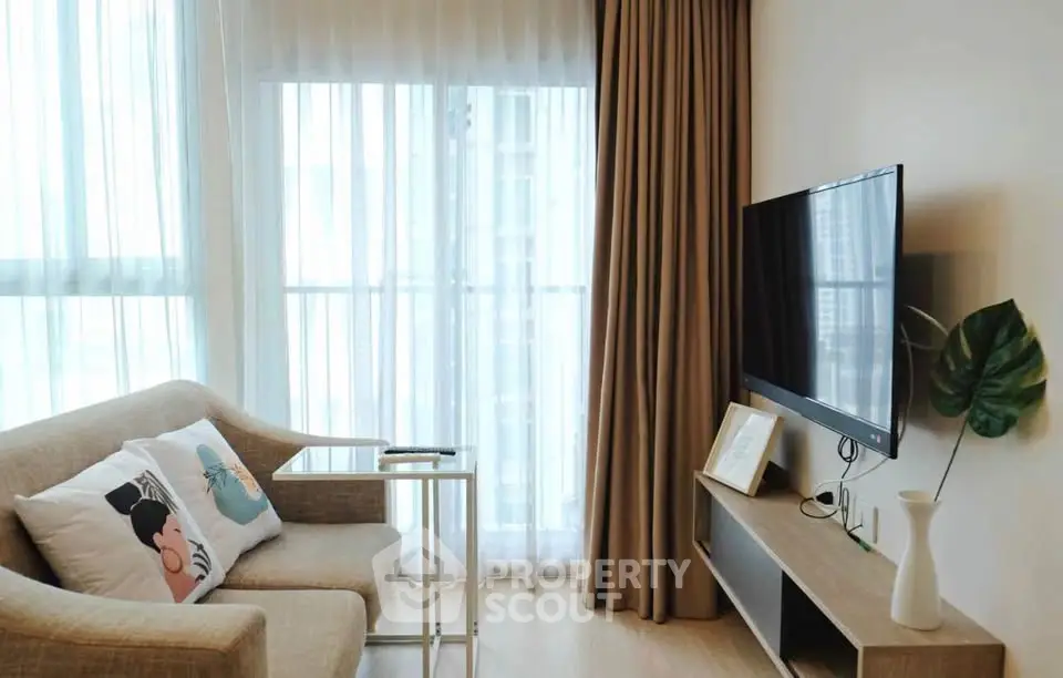 Cozy living room with modern decor and large window, featuring a stylish sofa and flat-screen TV.
