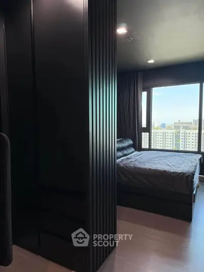 Modern bedroom with sleek black accents and large window offering city views.