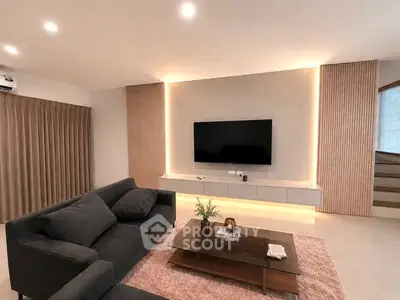 Modern living room with sleek design, featuring a wall-mounted TV, cozy sofa, and elegant lighting.