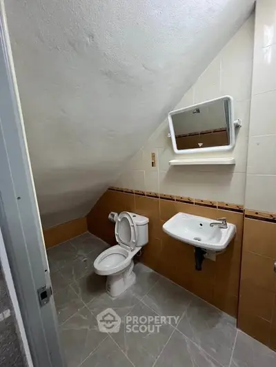 Compact attic bathroom with sloped ceiling and modern fixtures.