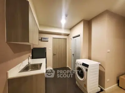 Modern kitchen with washing machine and sleek cabinetry in compact apartment.