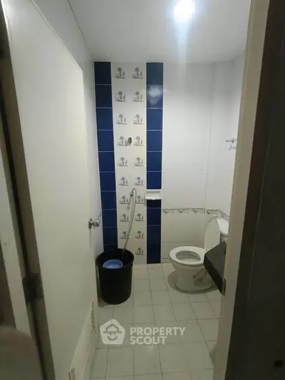 Compact bathroom with tiled walls and basic amenities in a real estate property.