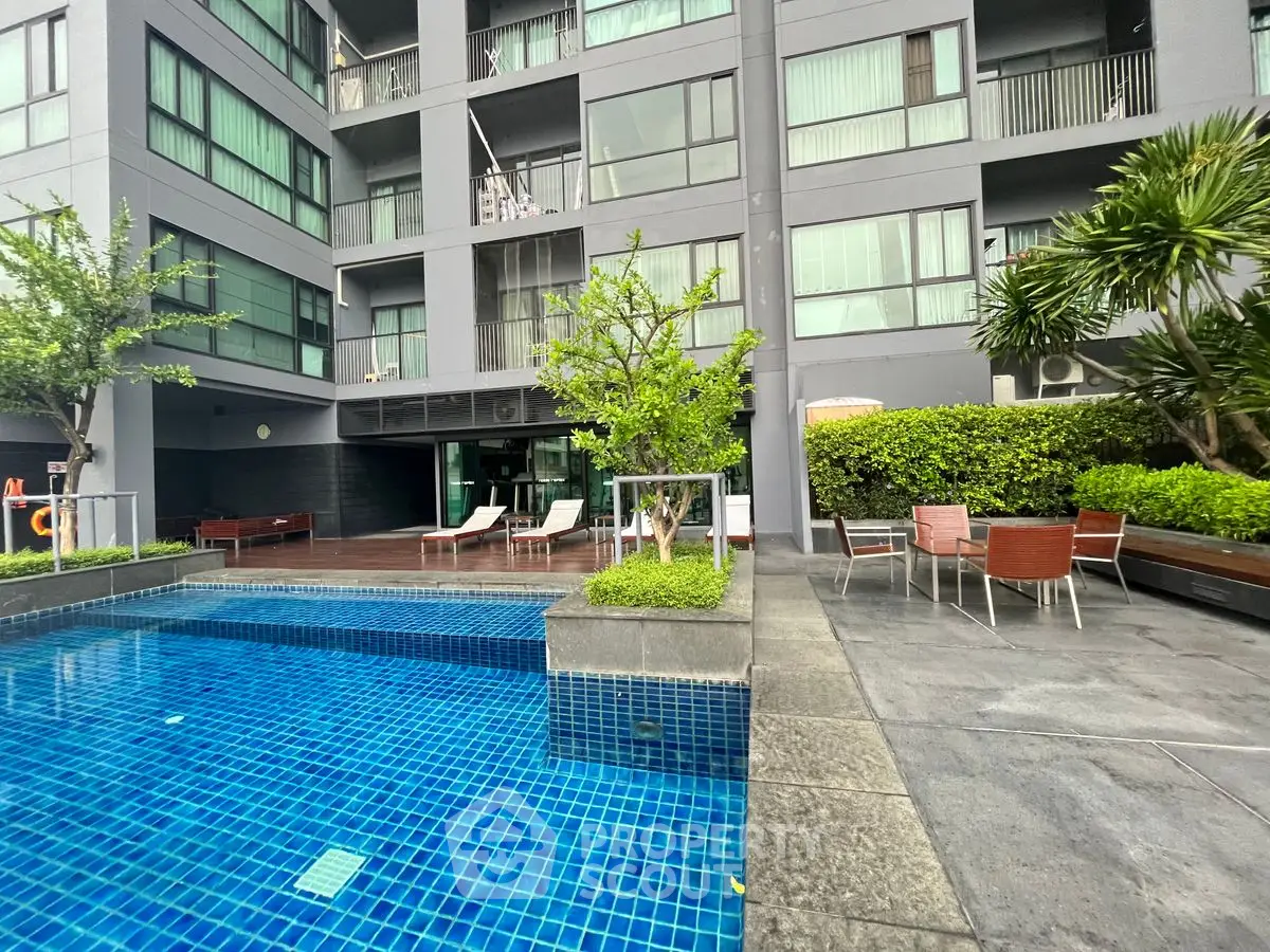 Modern apartment building with pool and outdoor seating area, lush greenery enhancing the ambiance.