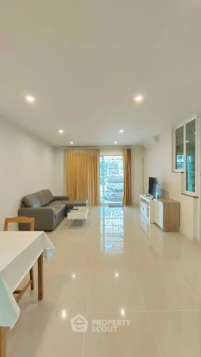Spacious modern living room with sleek furniture and large windows offering natural light.