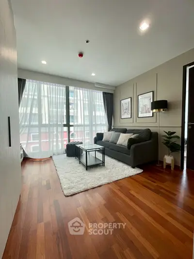Modern living room with wooden flooring and large windows in a stylish apartment.