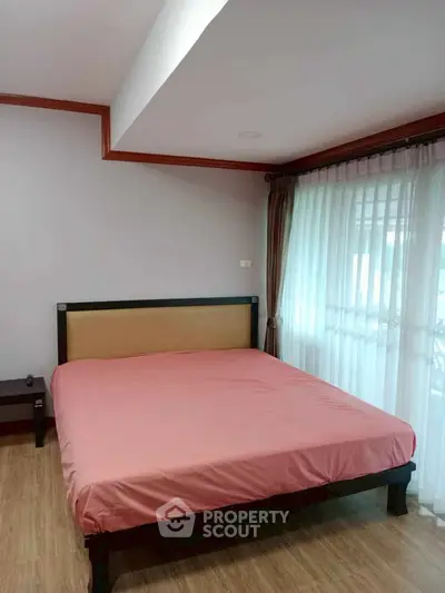 Spacious bedroom with large window and wooden flooring