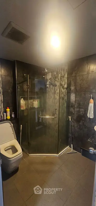 Modern bathroom with glass shower and sleek black tiles