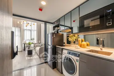 Modern kitchen with sleek appliances and open layout leading to stylish living room.
