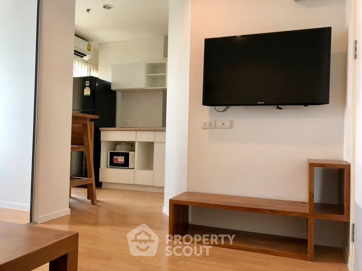 Modern apartment interior with wall-mounted TV and sleek kitchen design