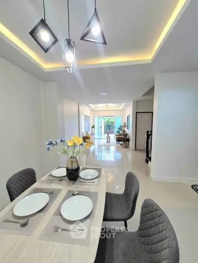 Modern dining area with elegant lighting and stylish decor in a spacious open-plan layout.
