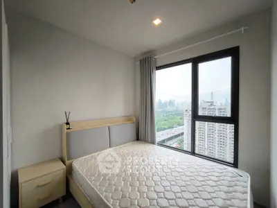 Modern bedroom with large window offering stunning city view in high-rise apartment.