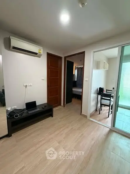 Modern apartment interior with air conditioning and wooden flooring, featuring a cozy dining area and sliding glass doors.