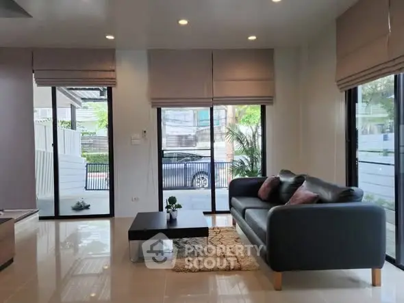 Modern living room with large windows and stylish furniture, offering a bright and inviting atmosphere.