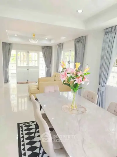 Spacious living room with elegant dining area and natural light, featuring modern decor and stylish curtains.