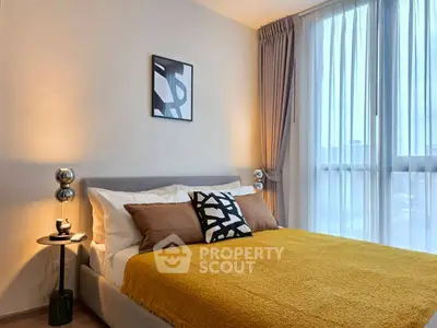 Modern bedroom with stylish decor and large window offering natural light.