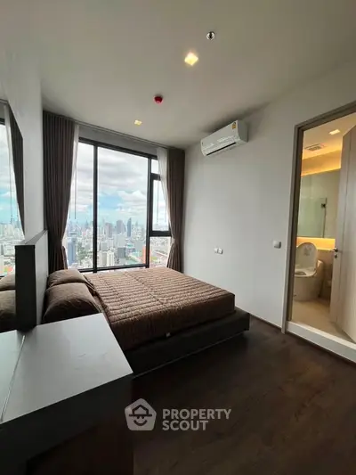 Modern bedroom with city view, featuring large windows and ensuite bathroom in a high-rise apartment.