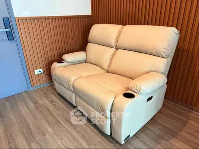 Luxurious beige recliner sofa in modern living room with wooden paneling and sleek flooring.