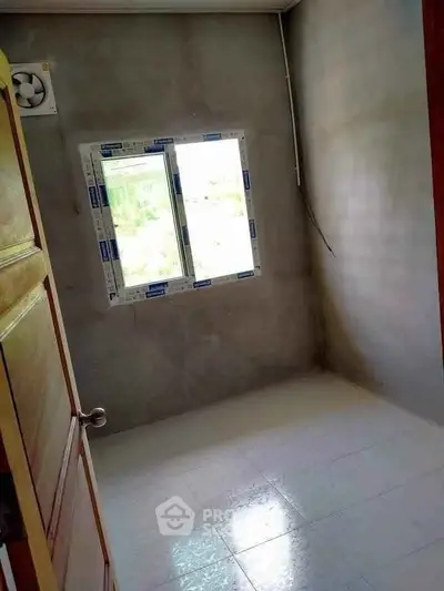 Compact room with tiled floor and window, ideal for storage or small office space.