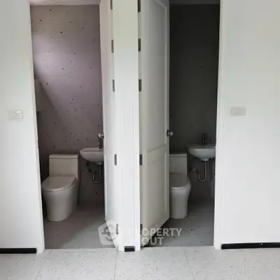 Dual bathroom setup with modern fixtures and minimalist design in a real estate property.