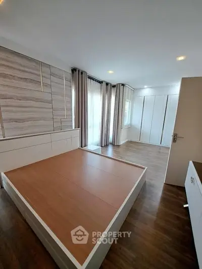 Spacious modern bedroom with wooden flooring and large windows