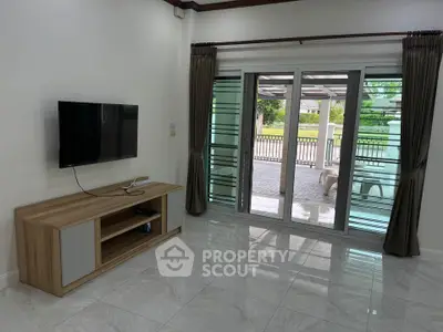 Spacious living room with modern TV setup and large sliding glass doors opening to patio.