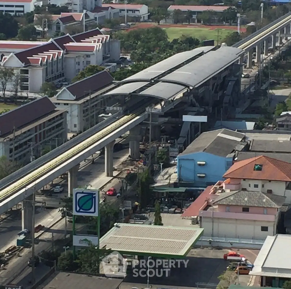 Aerial view of urban area with elevated train station and surrounding buildings.