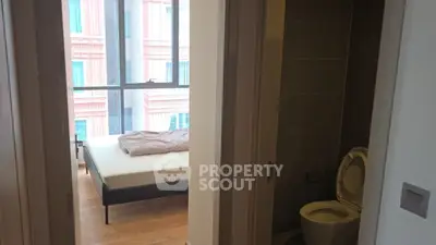 Modern apartment with bedroom and bathroom, featuring large windows and wooden flooring.