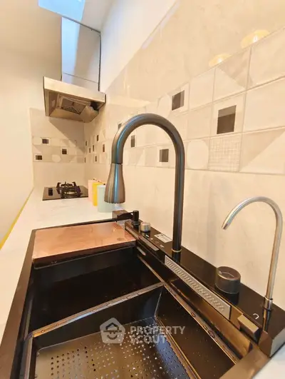 Modern kitchen with sleek black sink and gas stove, featuring stylish backsplash tiles.