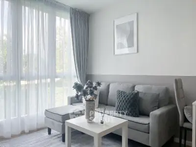 Modern living room with elegant gray sofa and large window view.