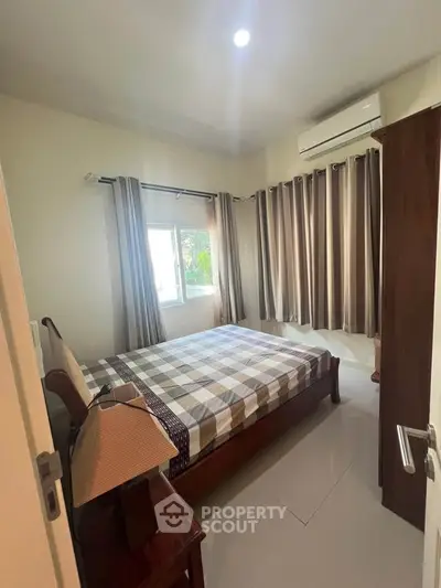 Cozy bedroom with natural light, featuring a comfortable bed and modern air conditioning.