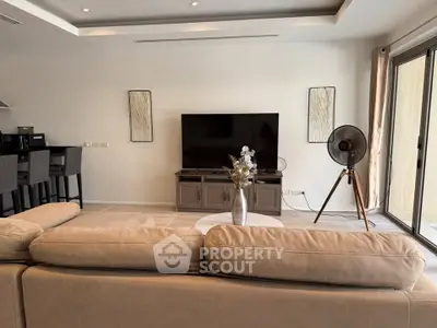 Spacious modern living room with elegant decor and large TV, perfect for relaxation and entertainment.