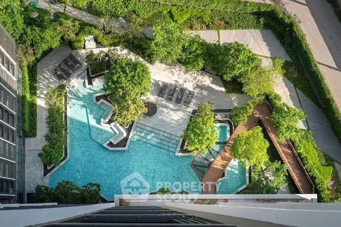 Stunning aerial view of a luxurious pool surrounded by lush greenery in a modern residential complex.