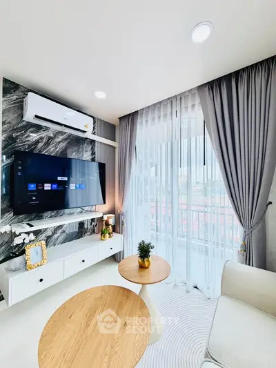 Modern living room with stylish decor, large TV, and natural light from floor-to-ceiling windows.