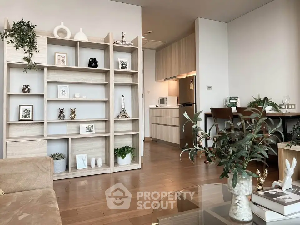 Modern living room with stylish shelving and open kitchen layout, featuring elegant decor and hardwood floors.